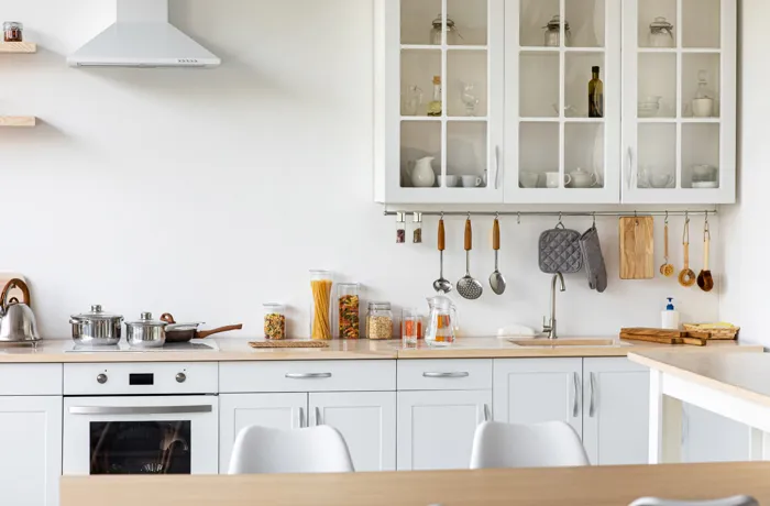 Minimalistyczna biała kuchnia z drewnianymi blatami i szafkami