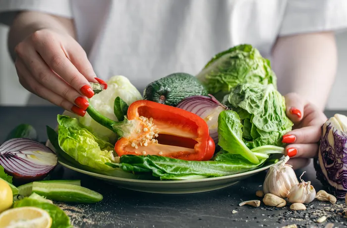 Talerz świeżych warzyw i sałat w kobiecych dłoniach