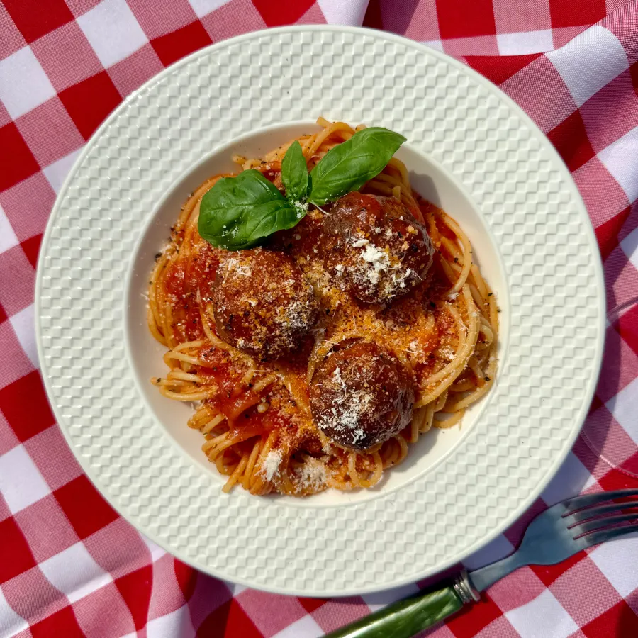 Makaron z klopsikami wege na widelcu na tle obrusa